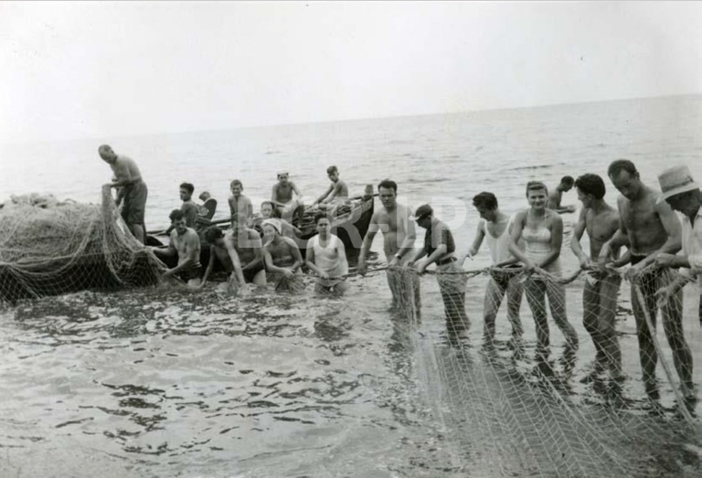 Children in the boat and women pulling the net to the shore with the men. Santa Croce (Trieste, Italy), 1954.