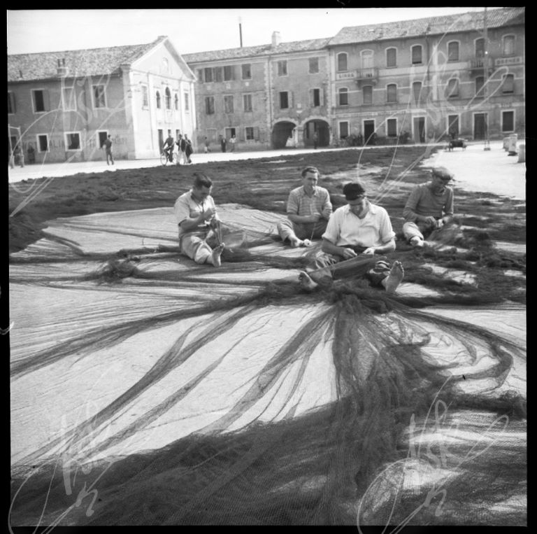Fishermen repairing the nets in the courtyard of the plants